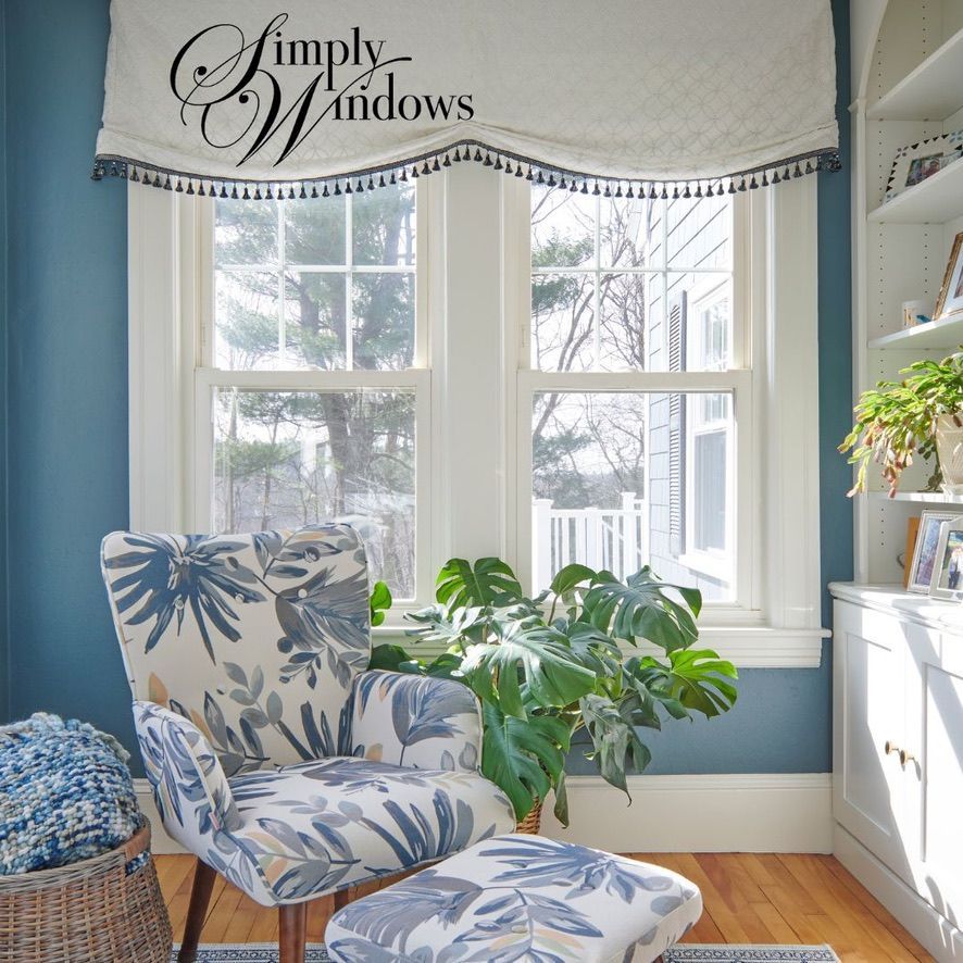 Cozy corner with blue walls, floral armchair, and large window with stylish valance.