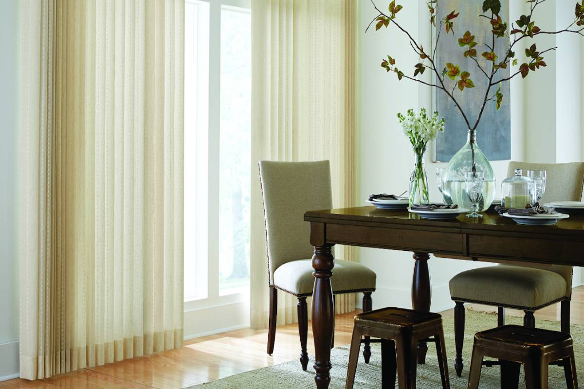a dining room with a table and chairs and vertical blinds Simply Windows.