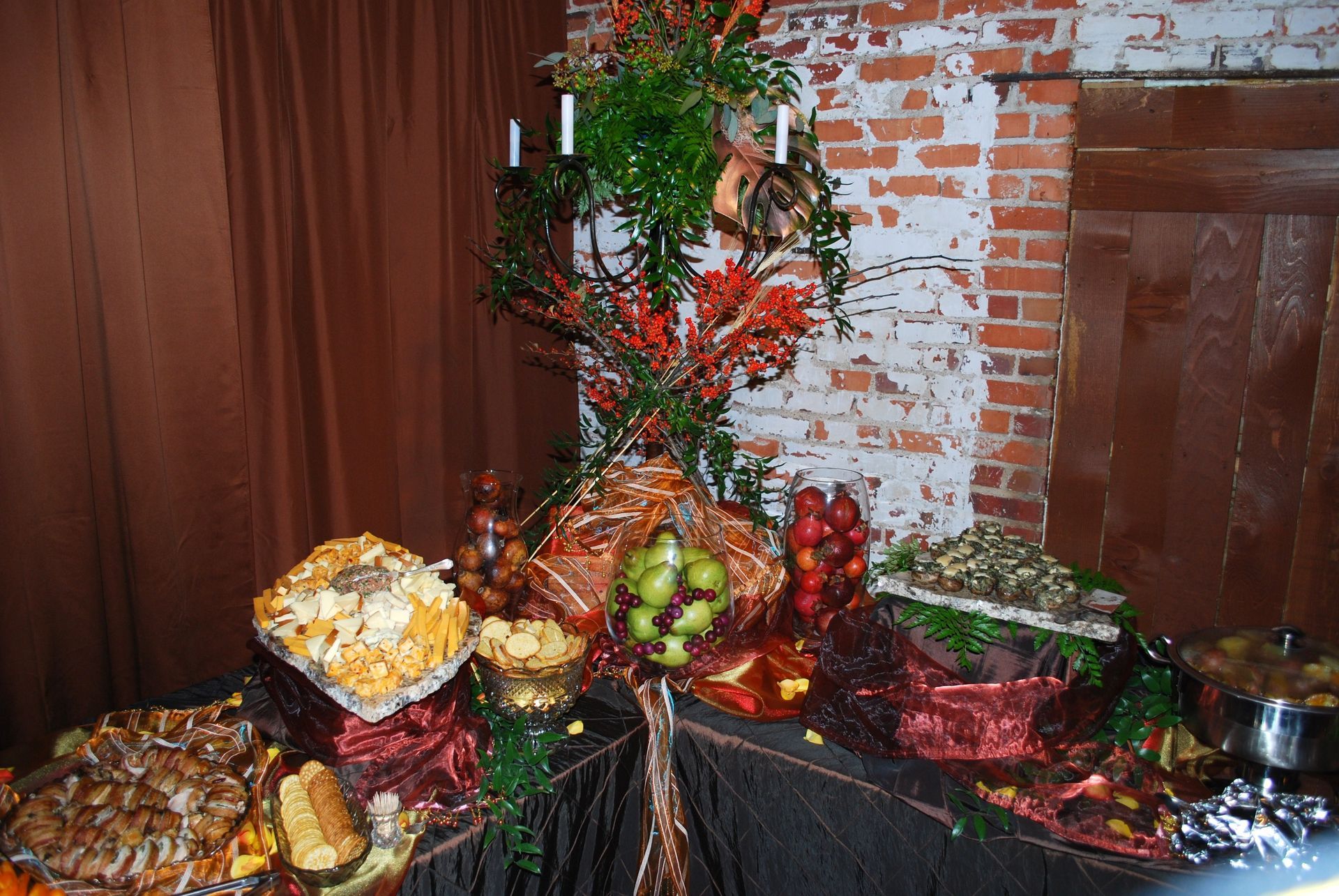 Decorative autumn harvest display with pumpkins, gourds, berries, and flowers on a black-draped table