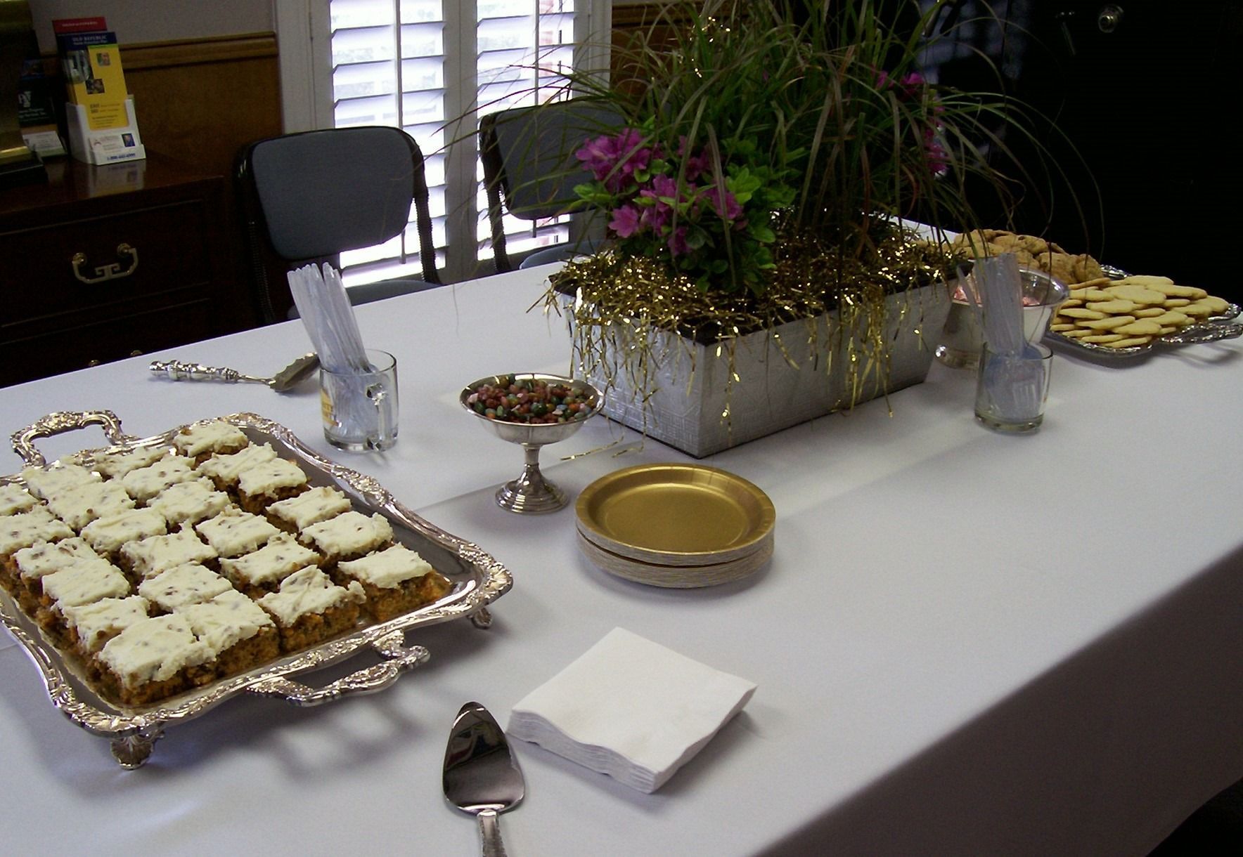 Table with dessert trays, bowls, and a floral centerpiece set for an event
