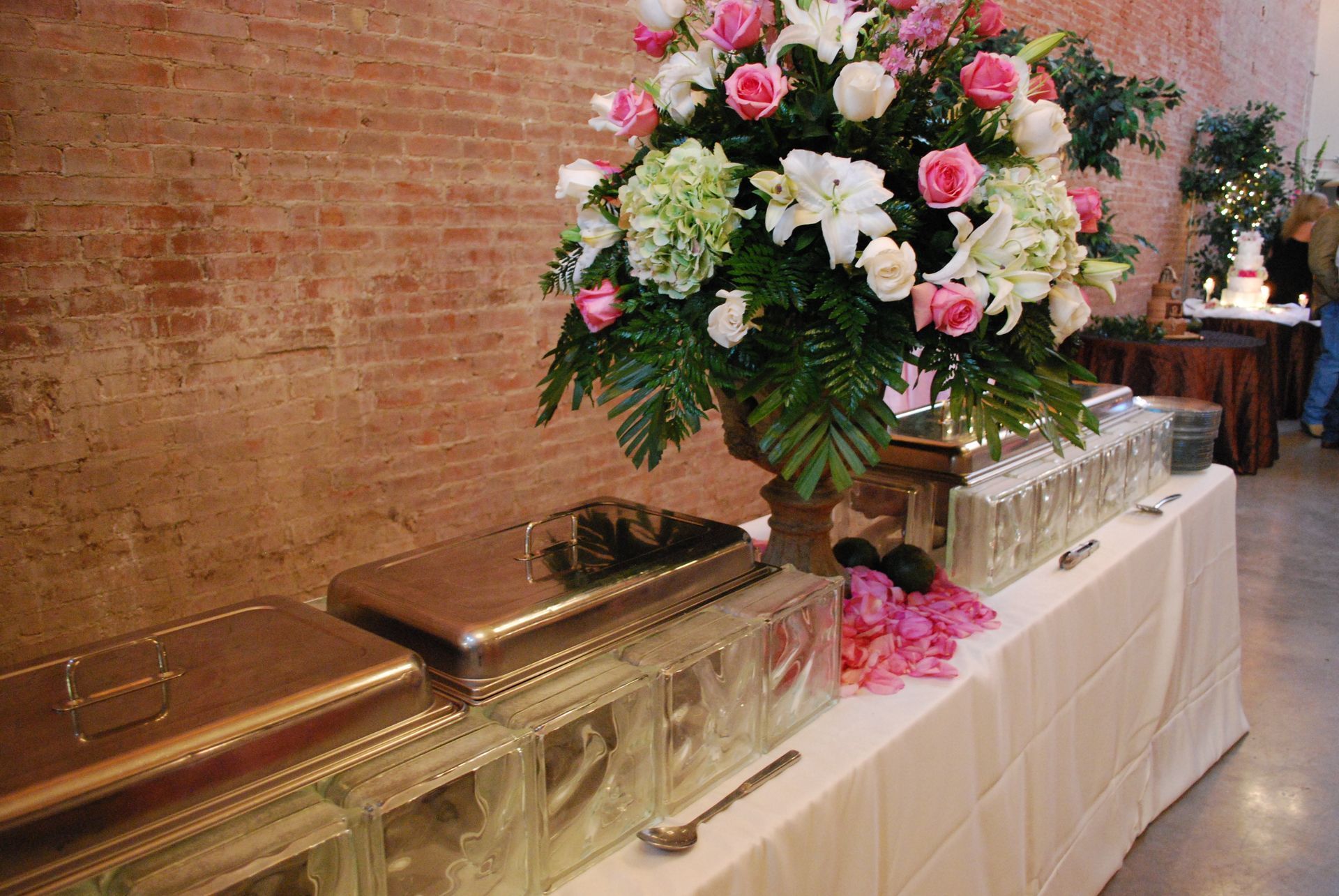 Floral funeral arrangement beside polished caskets on a white-draped table