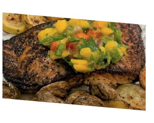 Grilled steak topped with colorful mango salsa, served with roasted potatoes and vegetables