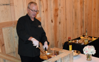 Chef carving meat at a buffet table beside trays and flowers in a wood-paneled room