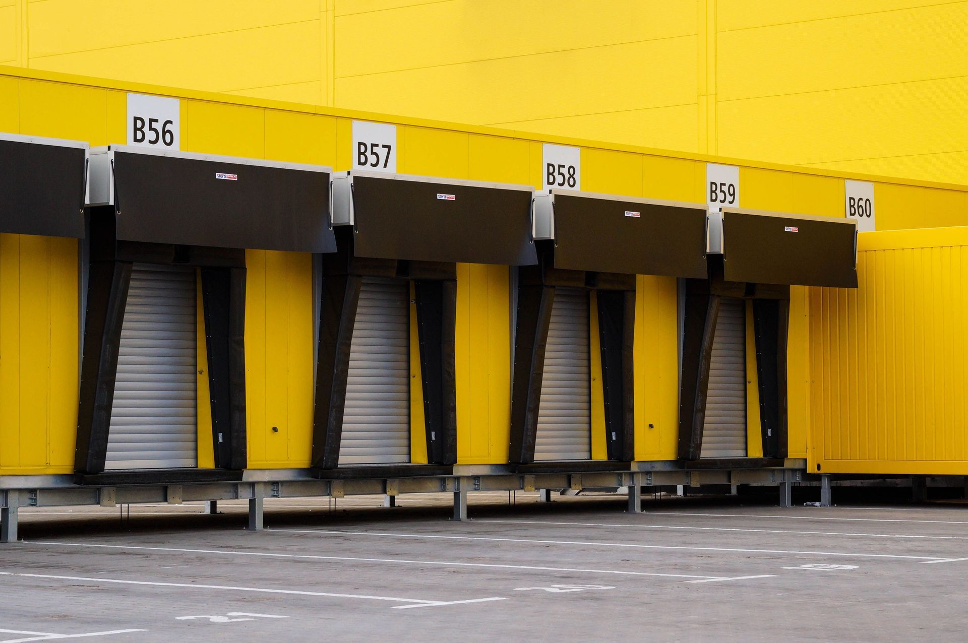 Yellow loading dock with four black-and-gray truck bays numbered 856, 857, 84, and 89.