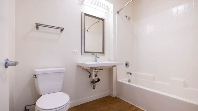 White bathroom with toilet, sink, bathtub, and a mirror.