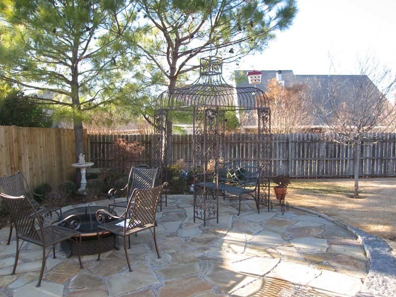 A stone patio with a fire pit and chairs