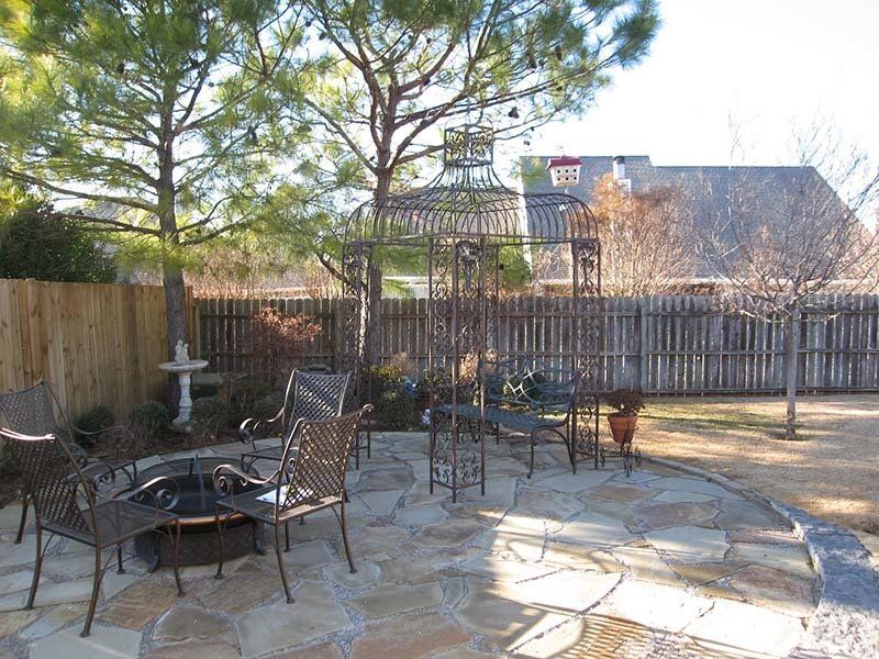 A stone patio with a fire pit and chairs