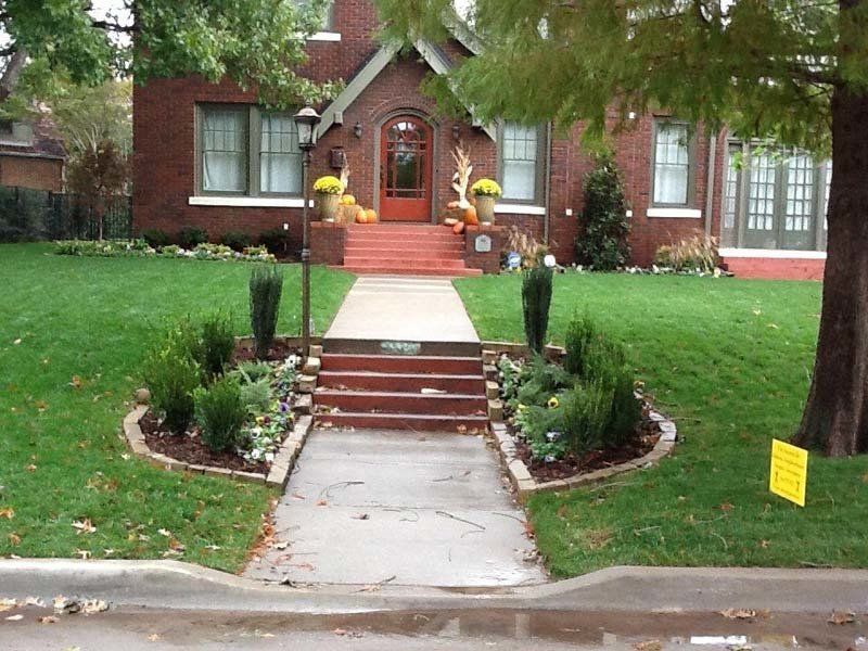 A brick house with a concrete walkway leading to the front door