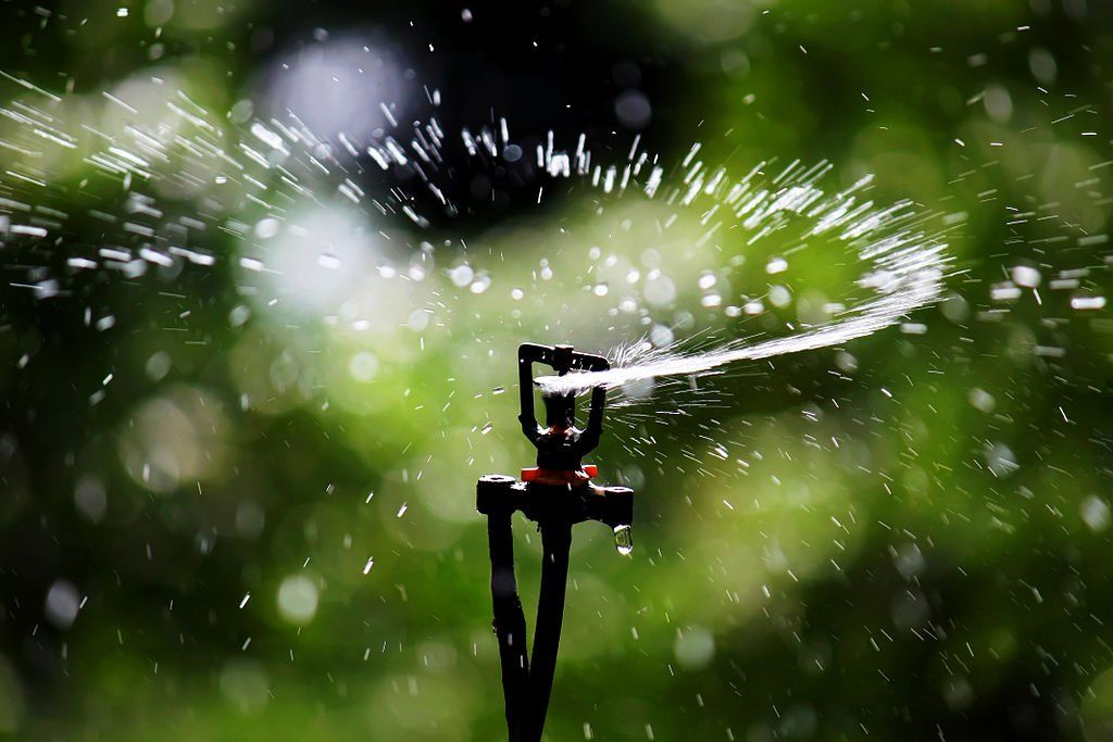 A sprinkler spraying water on a green background