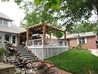A house with a large deck and a pergola in the backyard.