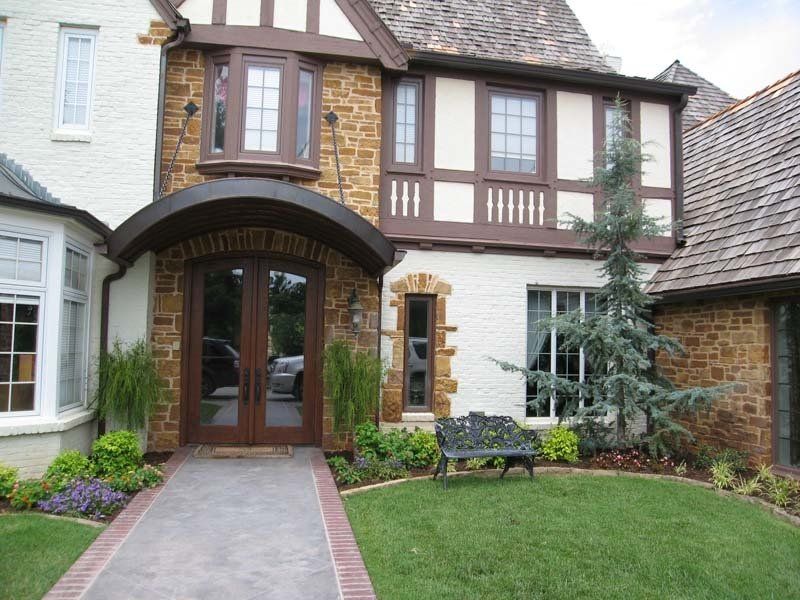 A brick and white house with a bench in front of it