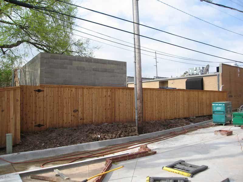 A wooden fence with a green dumpster in the background