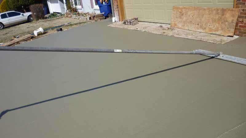 A concrete driveway is being built in front of a house.
