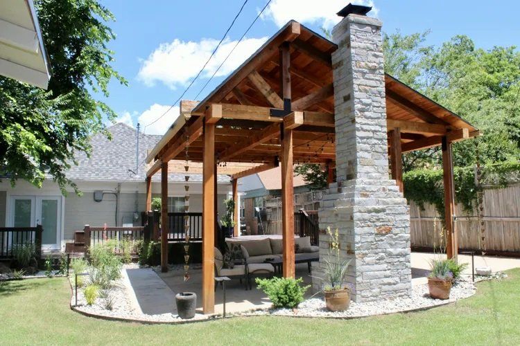 A wooden pavilion with a stone chimney in the backyard