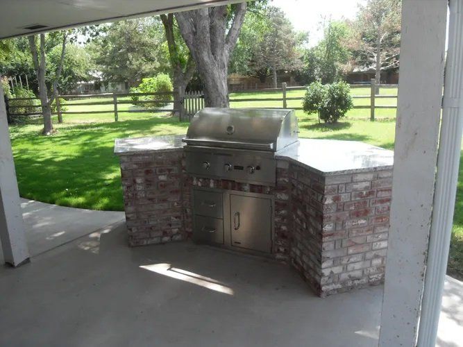 A grill is built into a brick wall under a covered area
