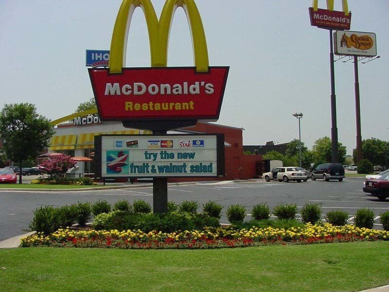 A McDonald 's restaurant with a sign that says try the new fruit & walnut salad