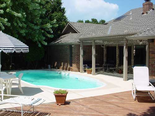 A backyard with a large swimming pool and chairs
