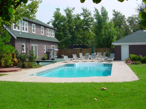 A large swimming pool is in the backyard of a house