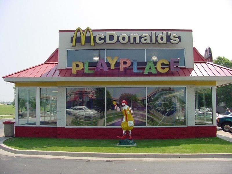 A McDonald 's restaurant with a statue of Ronald McDonald  standing in front of it