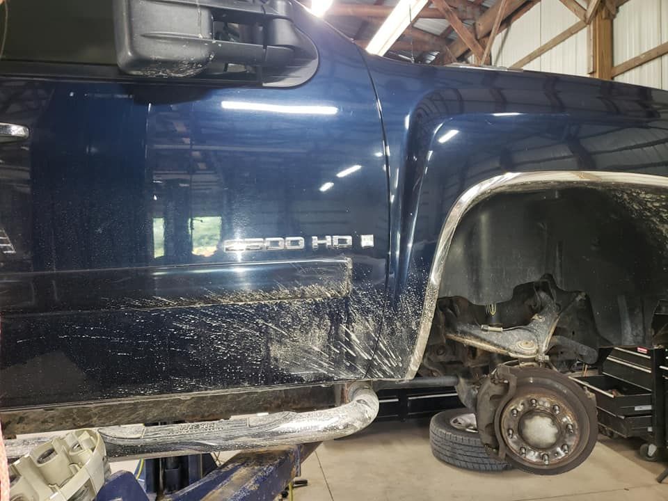 A blue truck is sitting on a lift in a garage.