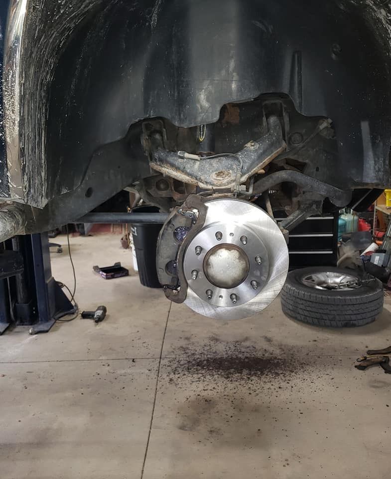A brake disc is being removed from a car in a garage