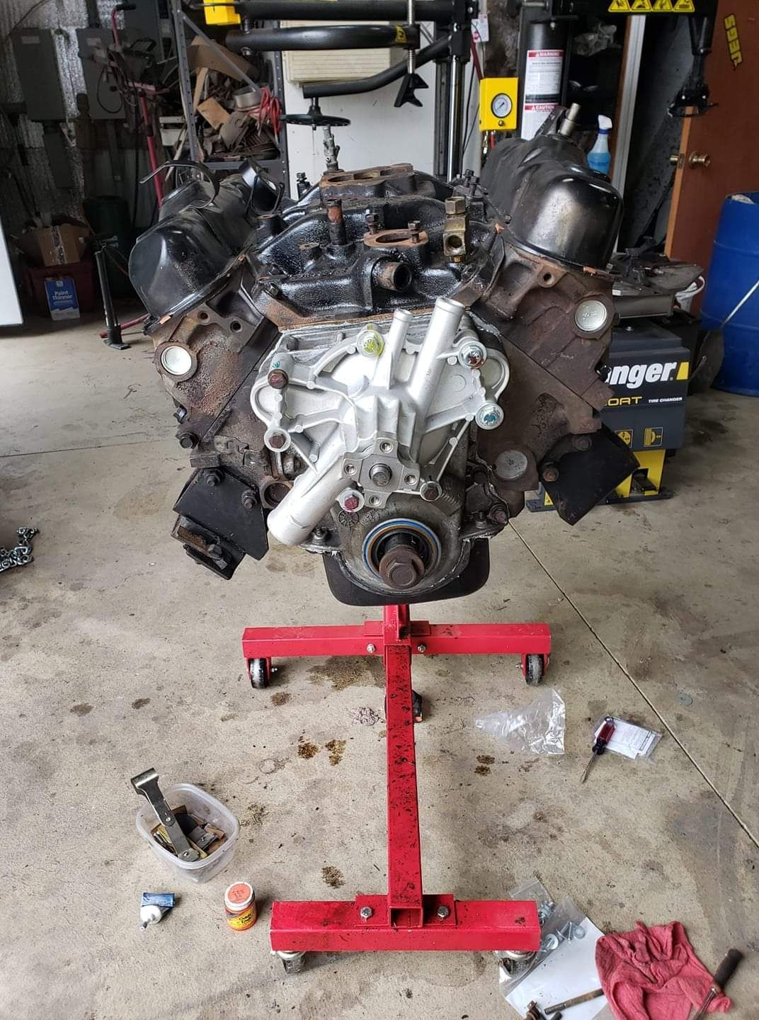 A engine is sitting on a red stand in a garage.