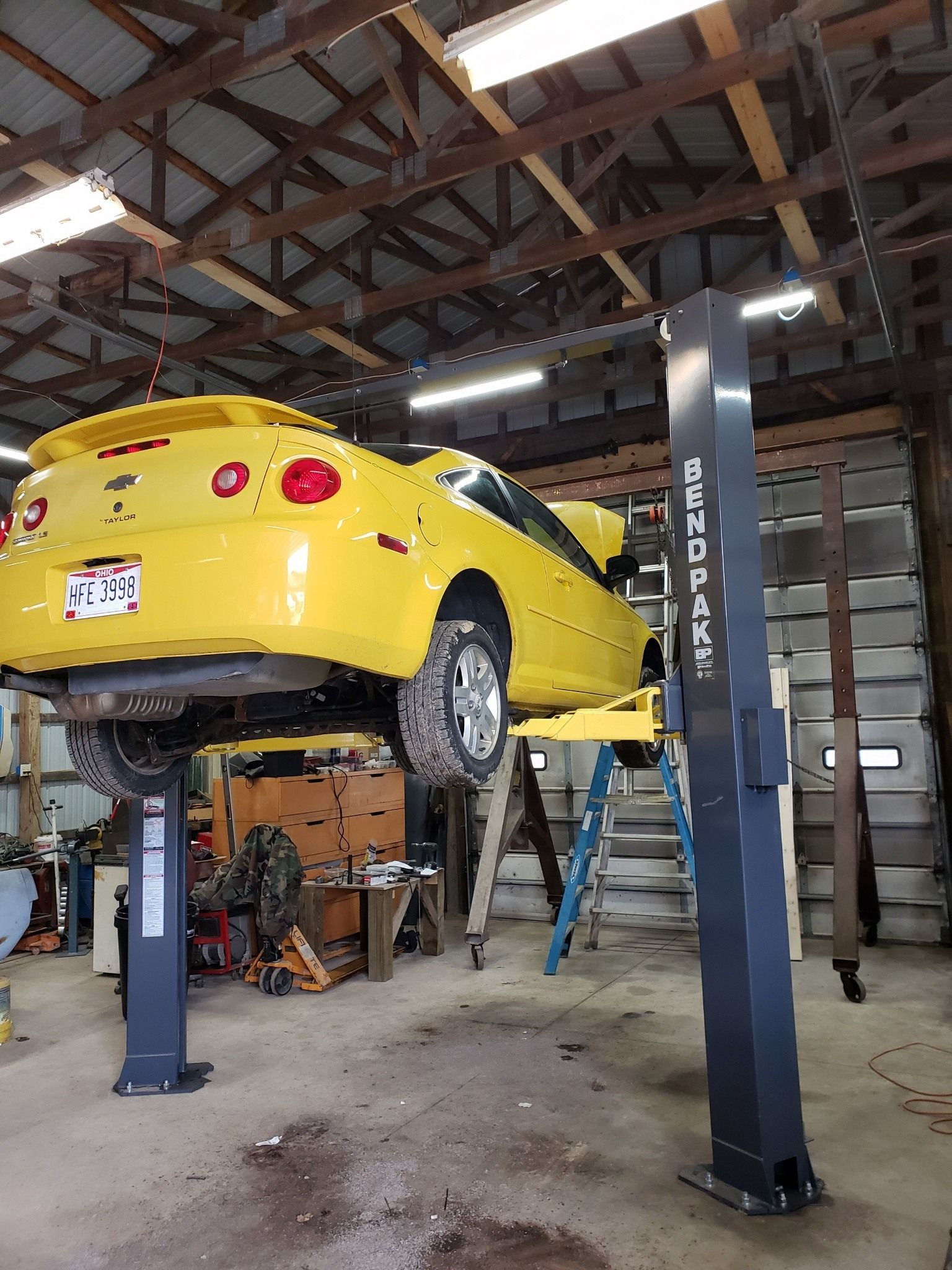 A yellow car is on a lift in a garage.