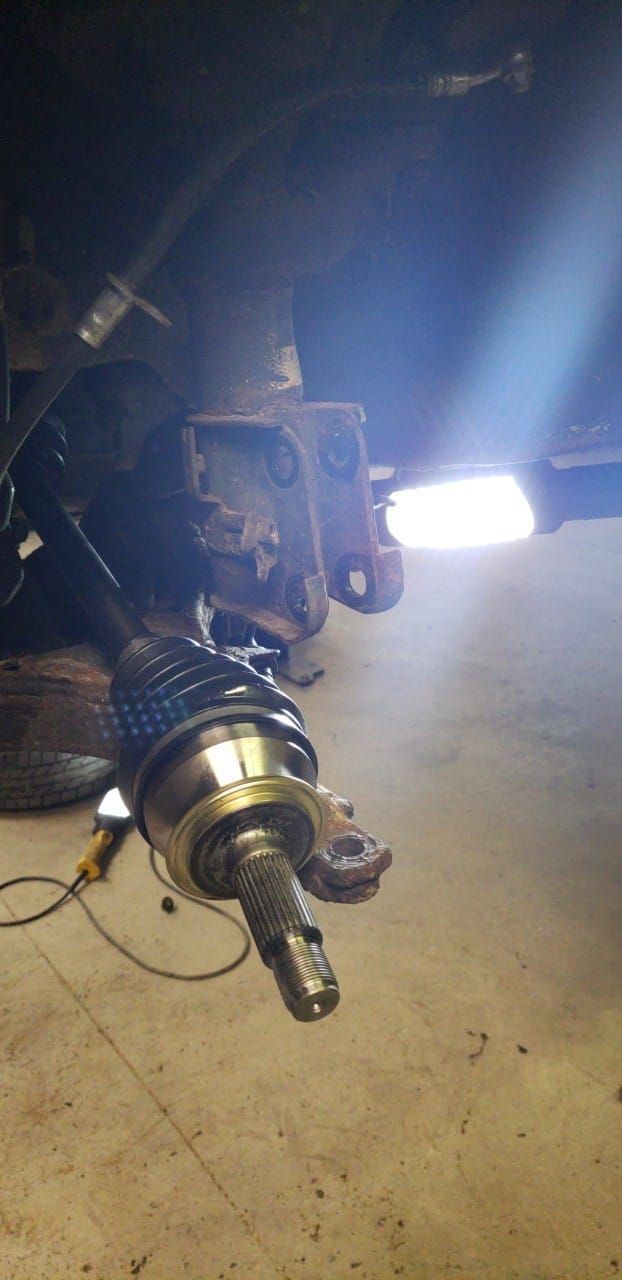 A close up of a drive shaft on a car in a garage.