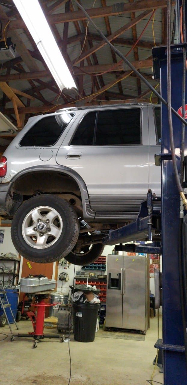 A silver suv is sitting on a lift in a garage.