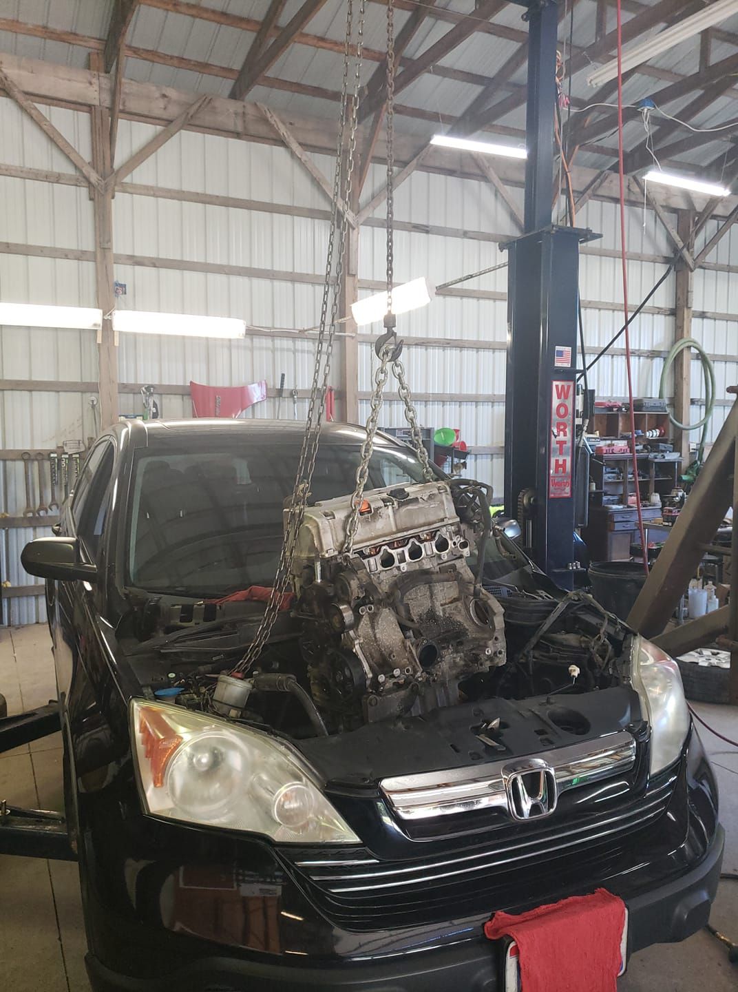 A car is being repaired in a garage with the engine removed.