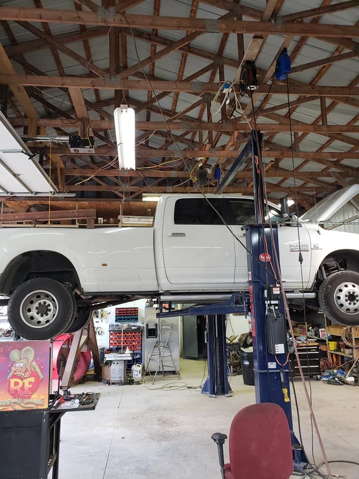 A white truck is sitting on a lift in a garage.