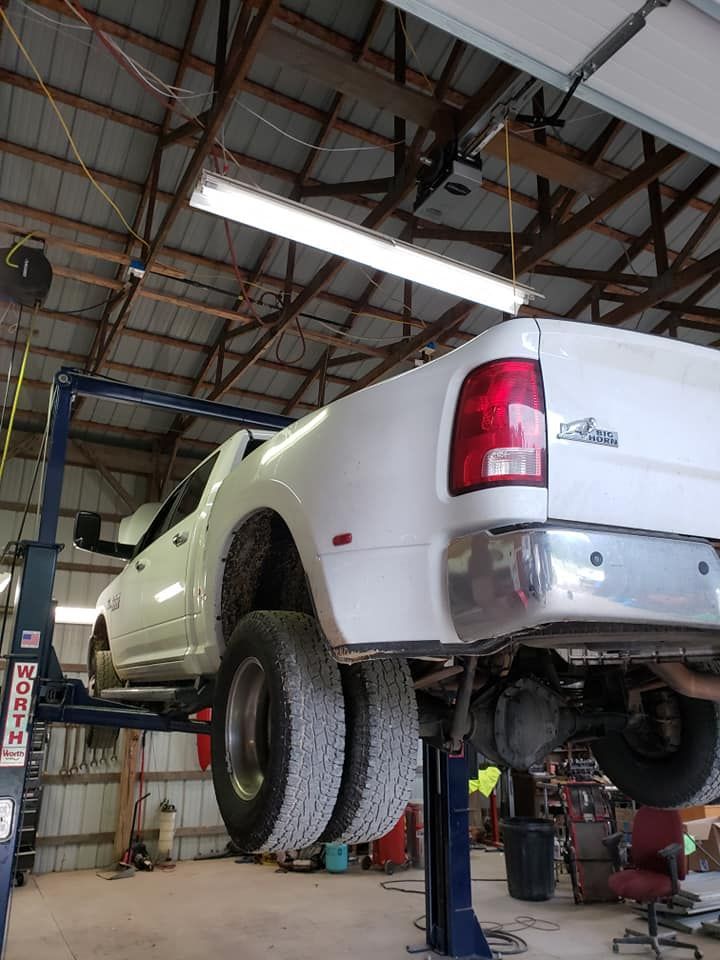 A white truck is sitting on a lift in a garage.