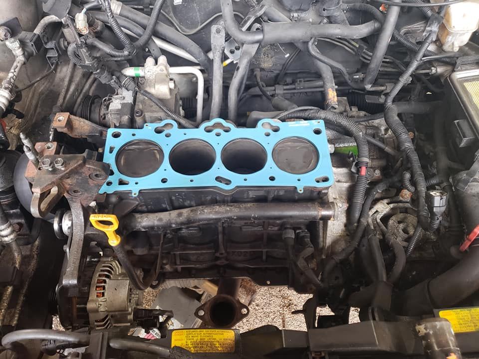 A close up of a car engine with a blue gasket on it.