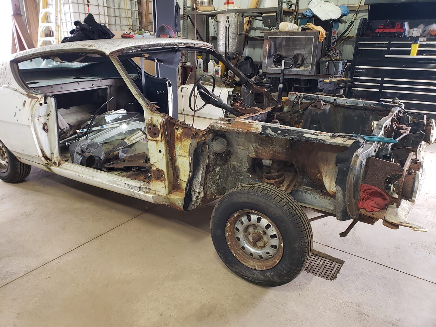 A white car is being dismantled in a garage.