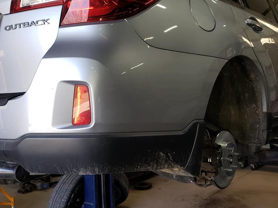A silver outback is sitting on a lift in a garage