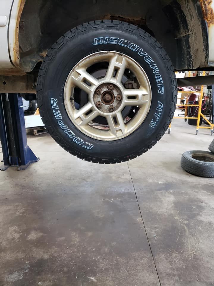 A car is sitting on a lift with a tire on it.