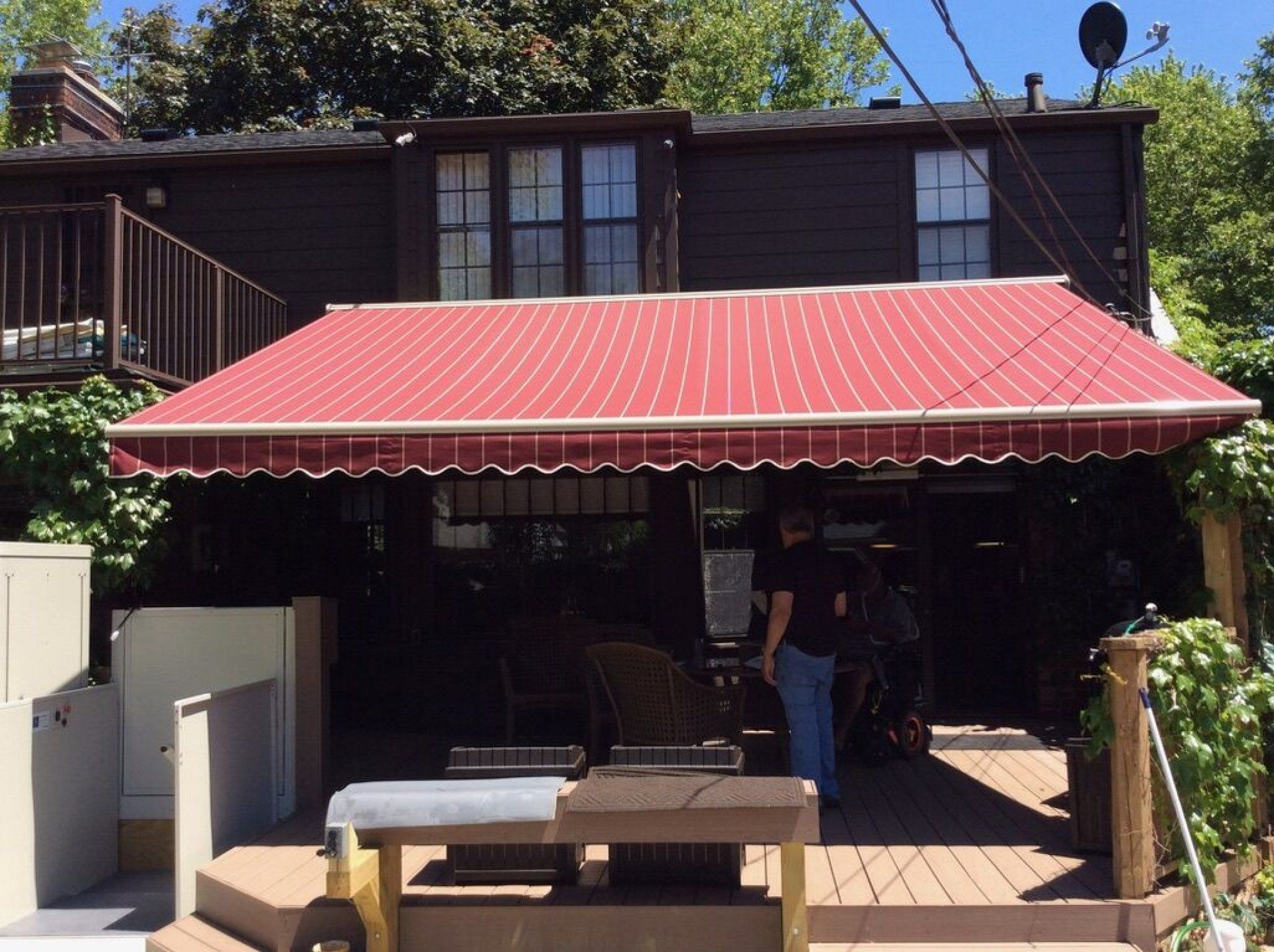 A man is standing under a red awning on a deck