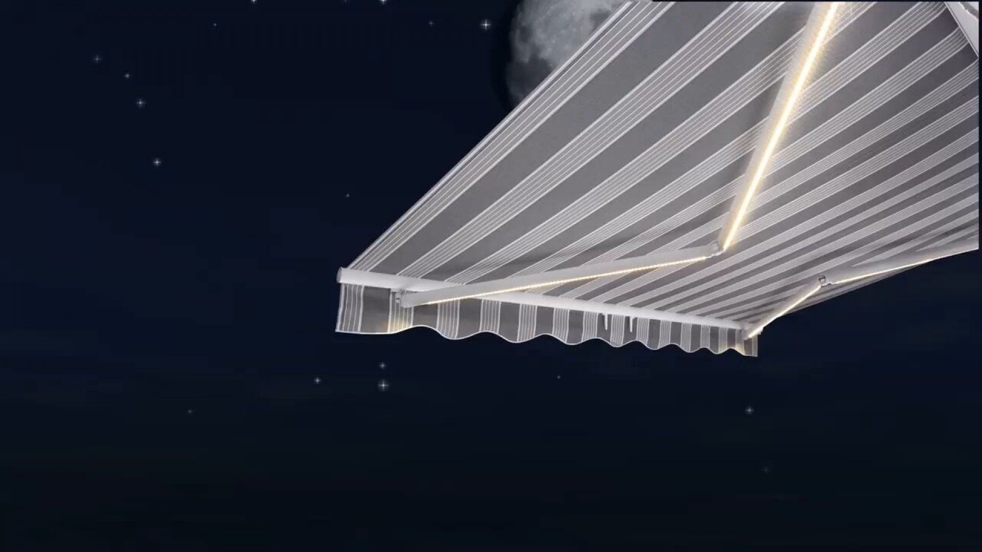 A striped awning with lights on it is against a dark night sky.