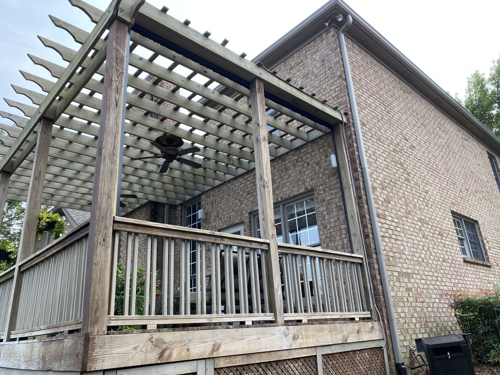 A large brick house with a wooden deck and pergola.