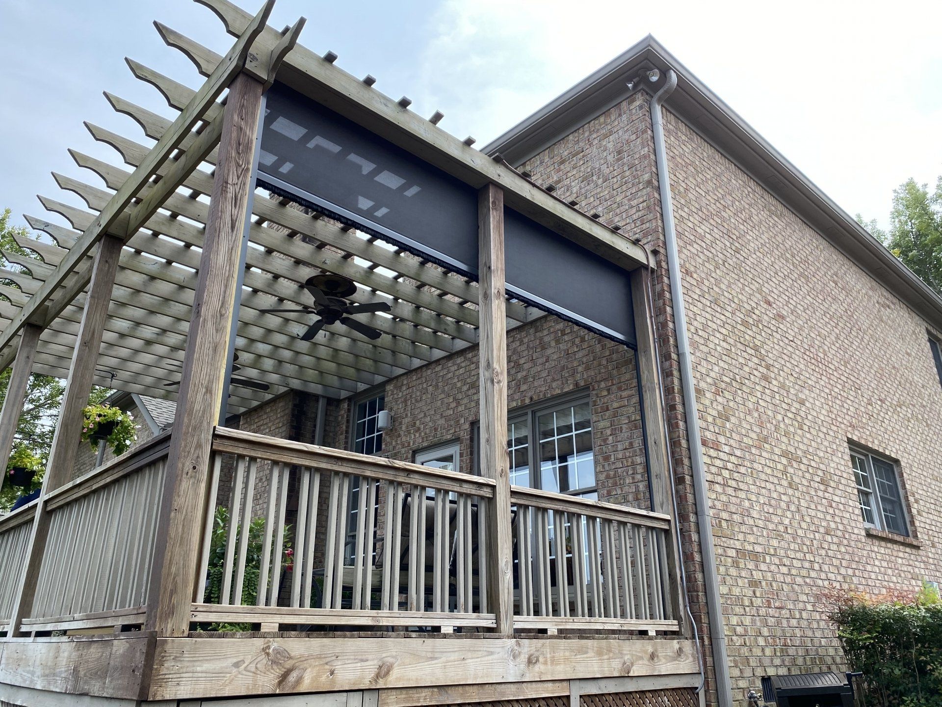 A large brick house with a screened in porch and a pergola.