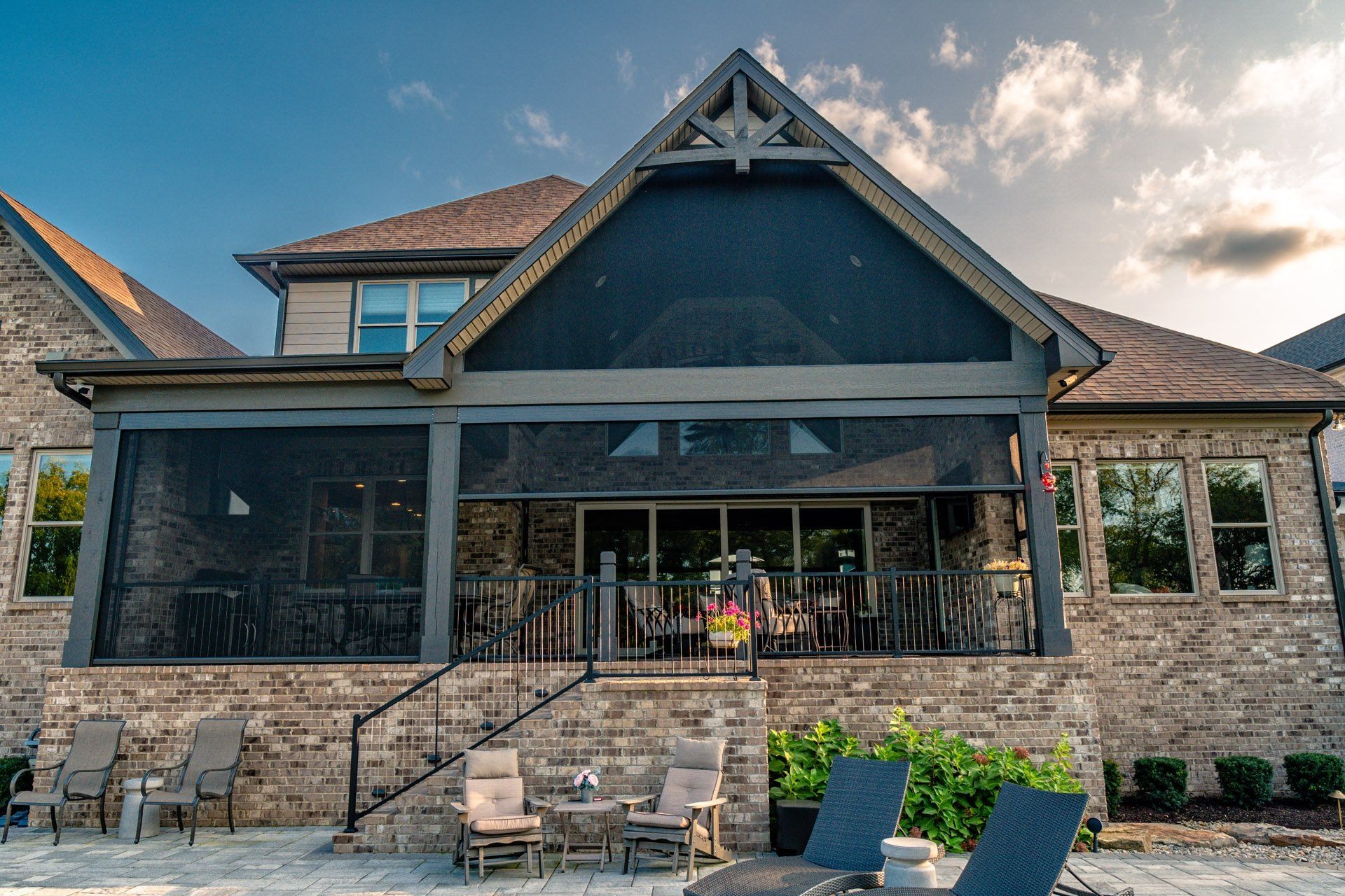 The back of a large brick house with a screened in porch.