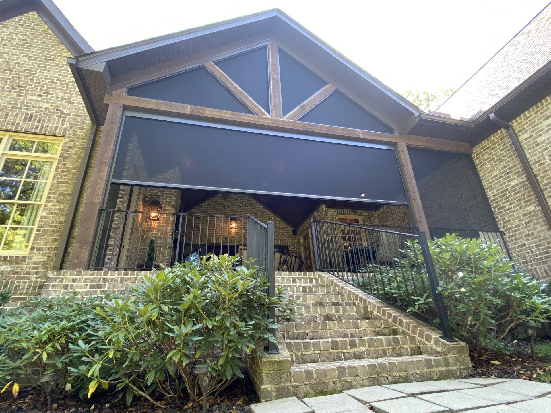 A large brick house with a screened in porch and stairs leading up to it.