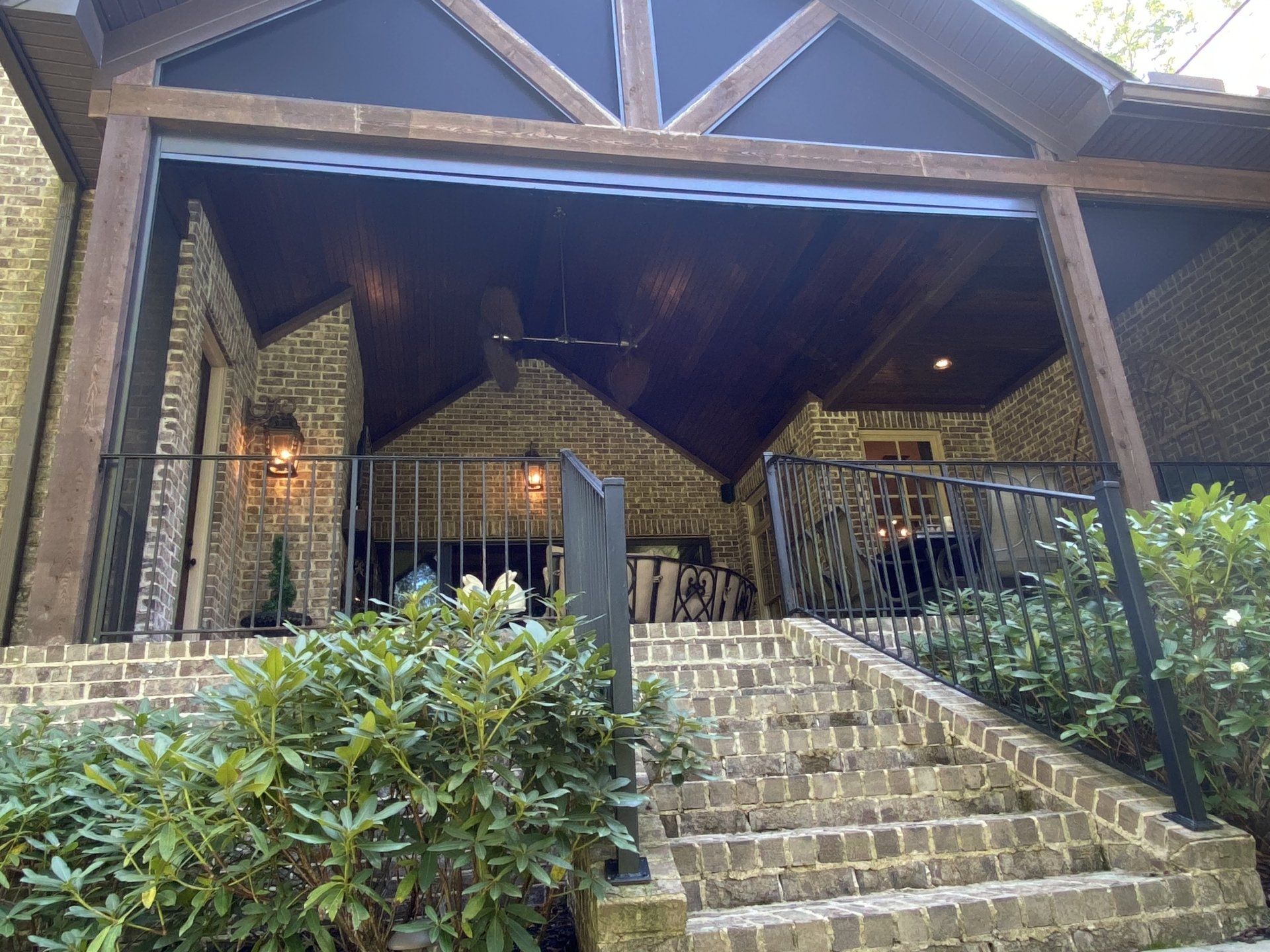 A brick house with a screened in porch and stairs leading up to it.