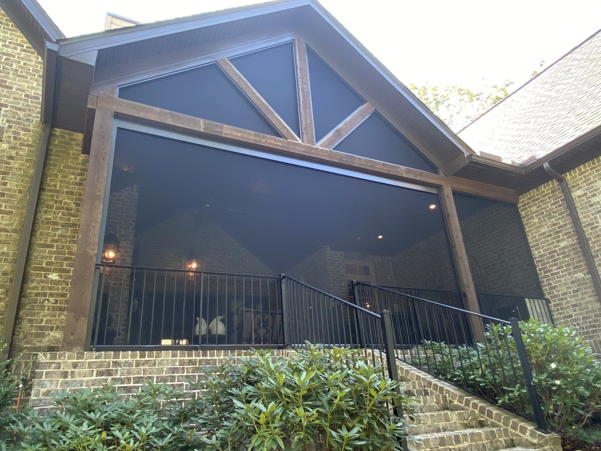 A brick house with a screened in porch and stairs leading up to it.