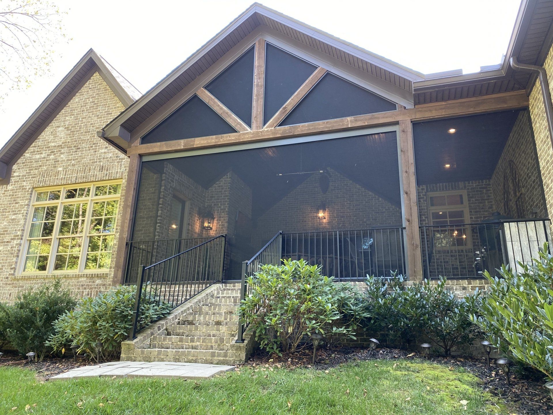 A large brick house with a screened in porch and stairs.