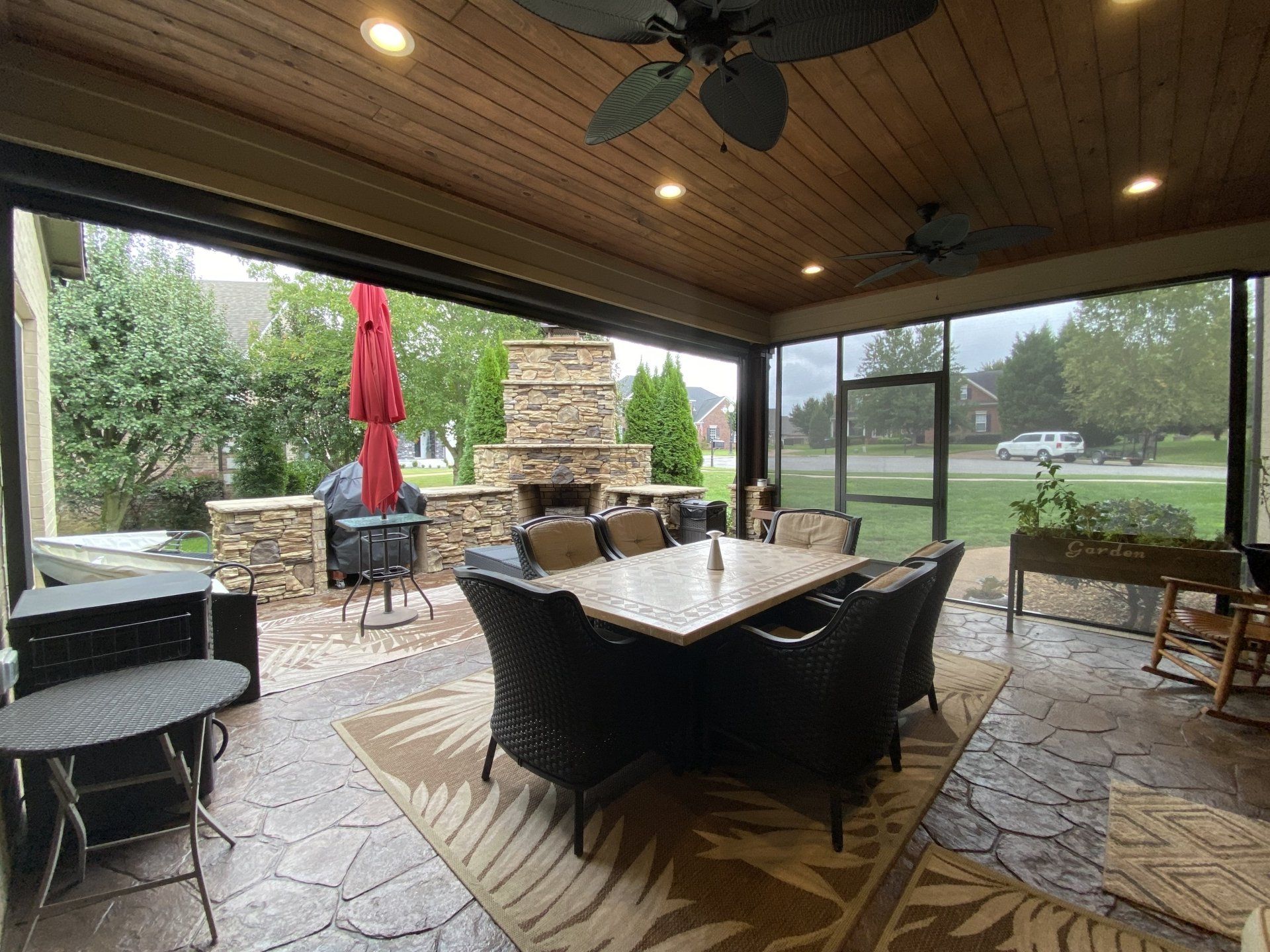 A screened in porch with a table and chairs and a fireplace.