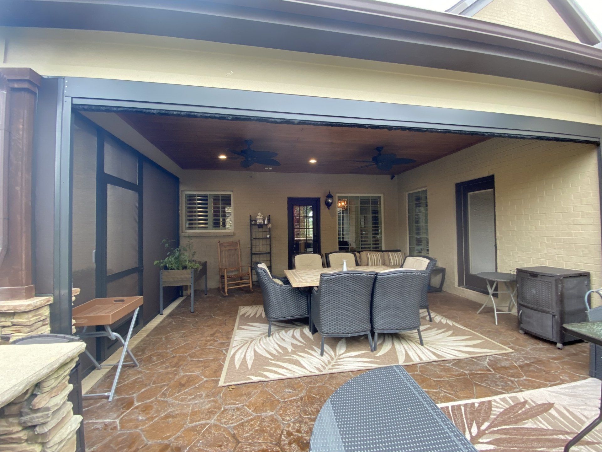 A patio with a table and chairs and a screened in porch.