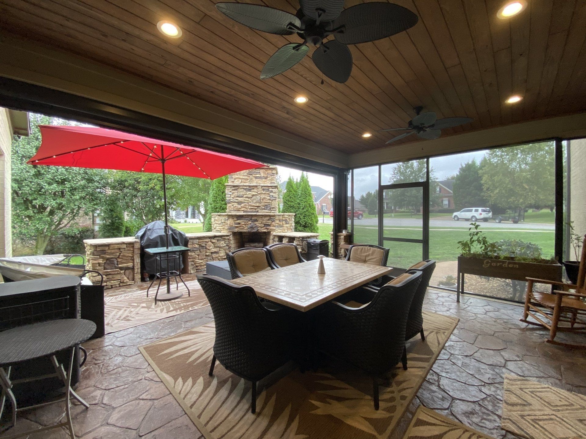 A screened in porch with a table and chairs and a red umbrella.
