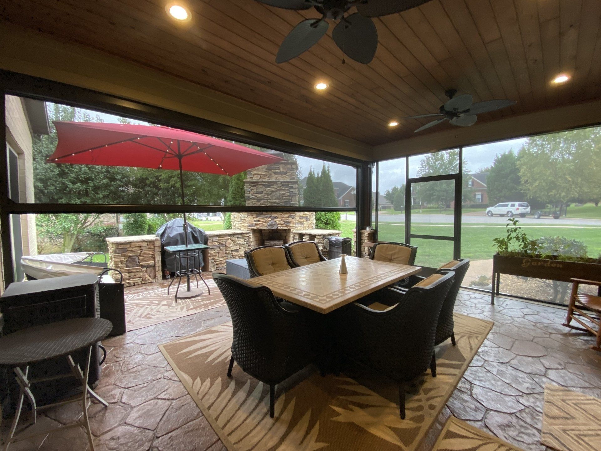 A screened in porch with a table and chairs and a red umbrella.