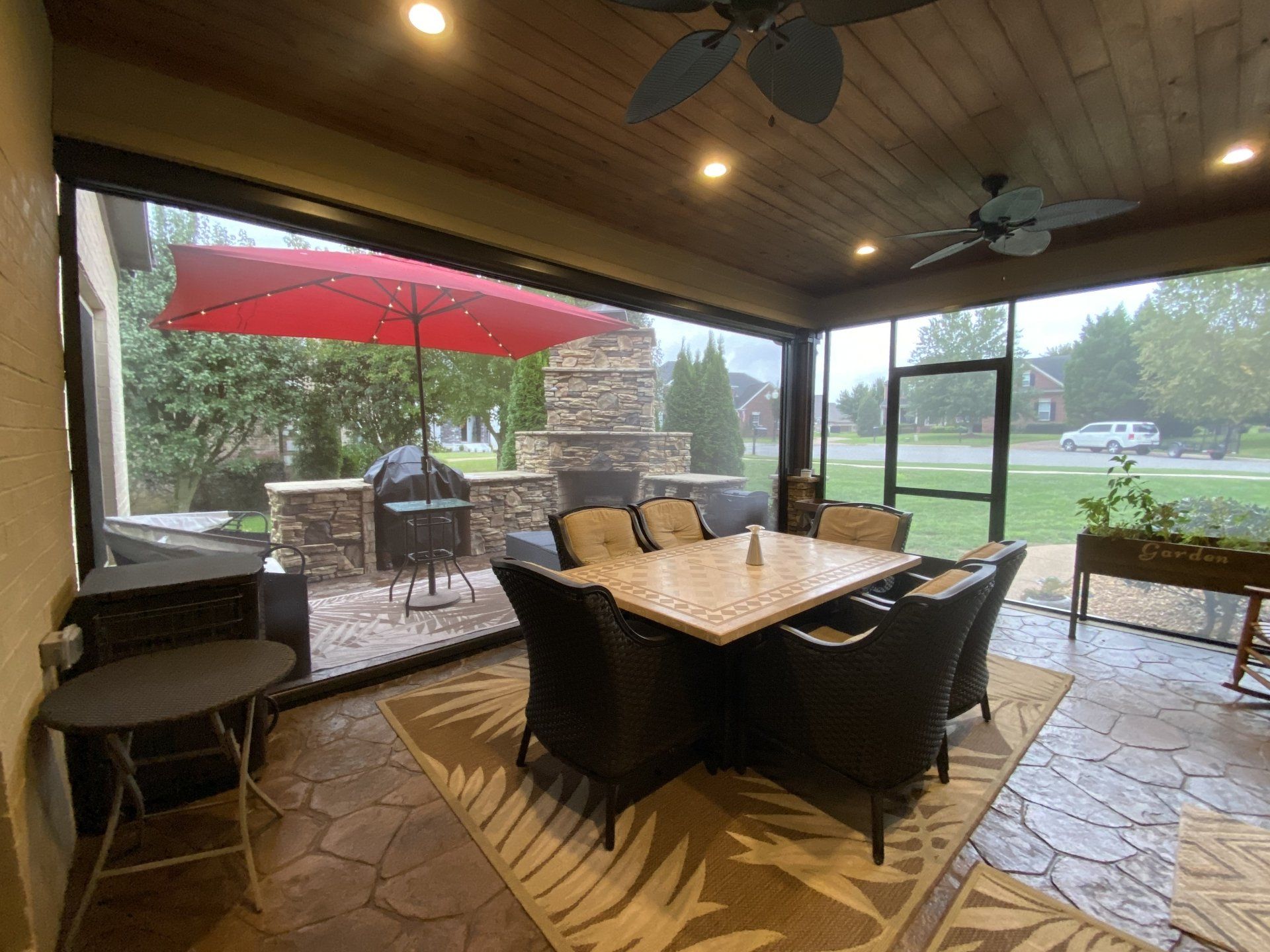A screened in porch with a table and chairs and a red umbrella.